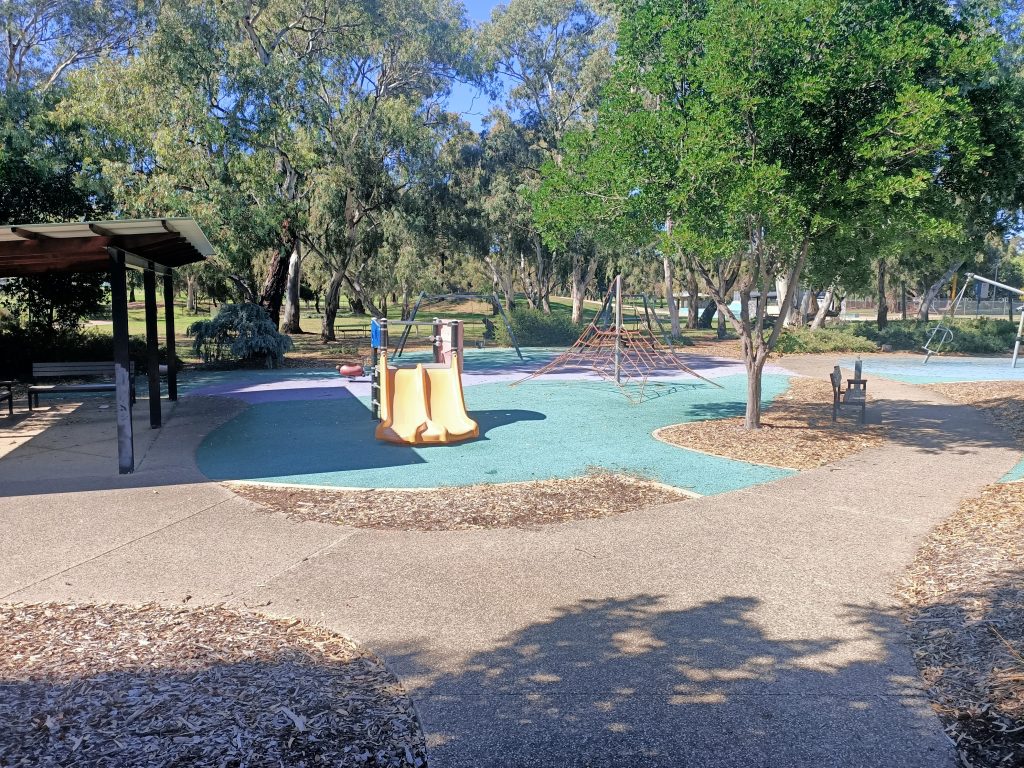 Small yellow slide, regency park trees in the background.