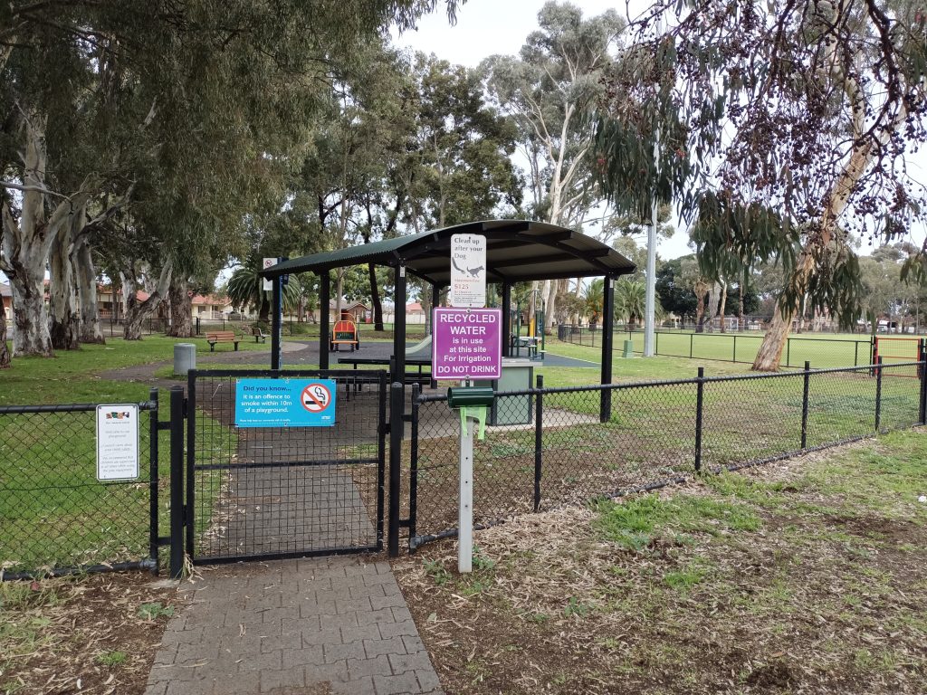 Wire fence and gate surrounding playground and trees
