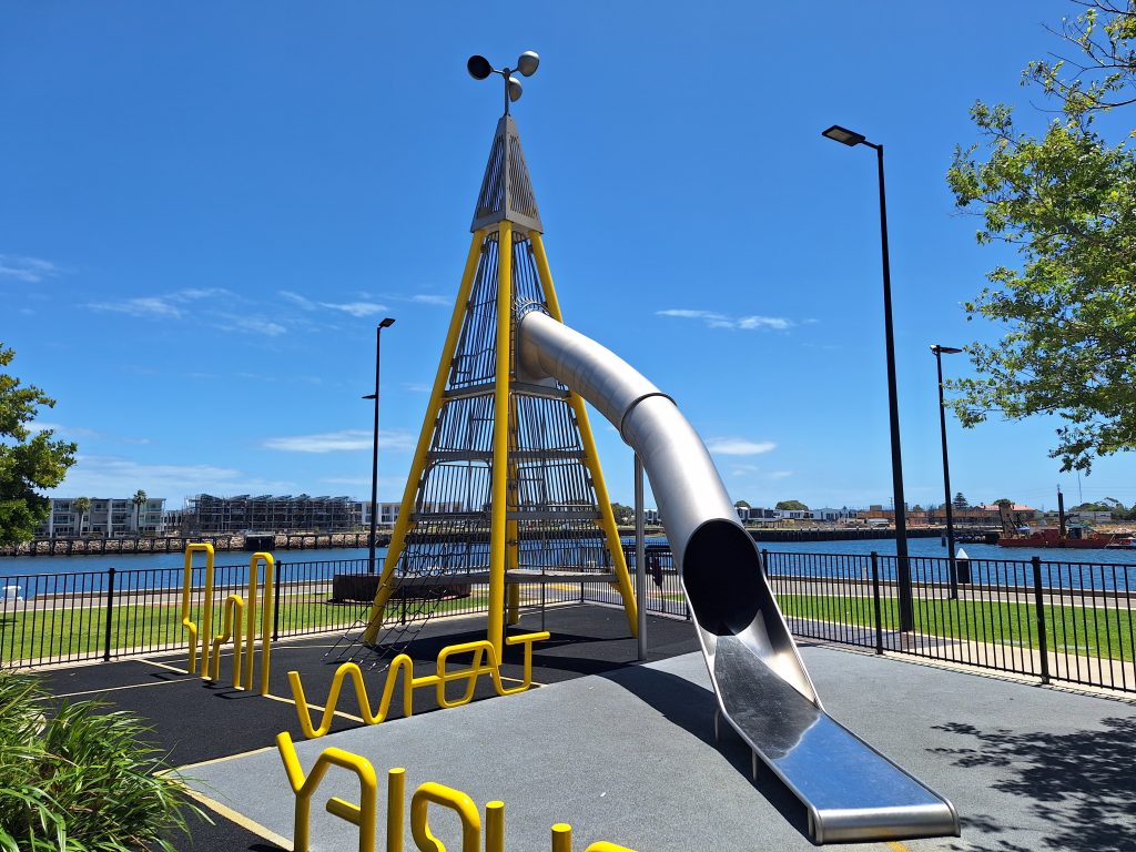 yellow slide at harts mill playground, port river in background.