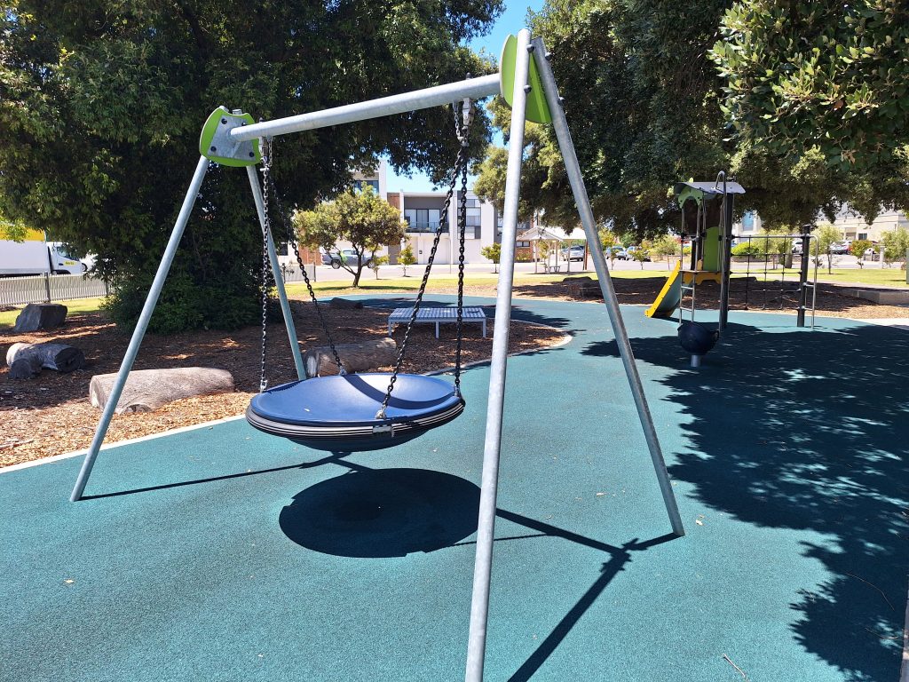 Blue Next swing, surrounded by trees.